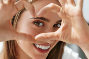 a woman smiling through a hand heart after getting dental fillings and sealants in humble tx